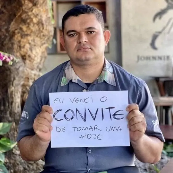 Meme de homem segurando cartaz sobre convite de tomar uma hoje, com expressão séria