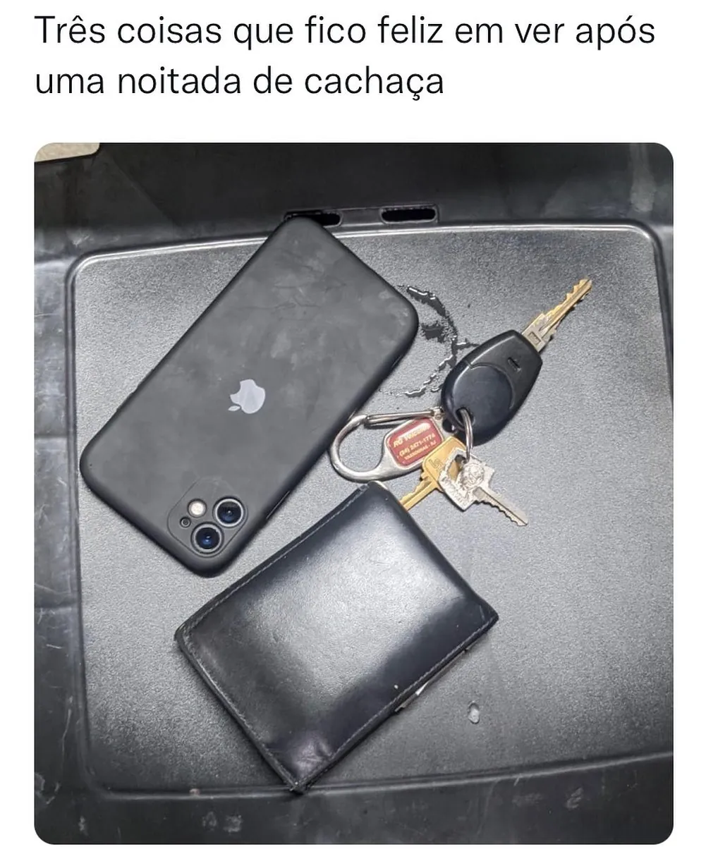 Meme de três coisas após uma noitada de cachaça: celular, carteira e chaves sobre uma superfície escura.